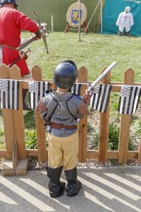Petit garçon habillé en costume moyenâgeux, regardant une animation médiévale avec des archers durant la fête des 900 ans du marché de la Guerche-de-Bretagne. Samedi 4 septembre 2021. Petit garçon habillé en costume moyenâgeux, regardant une ani