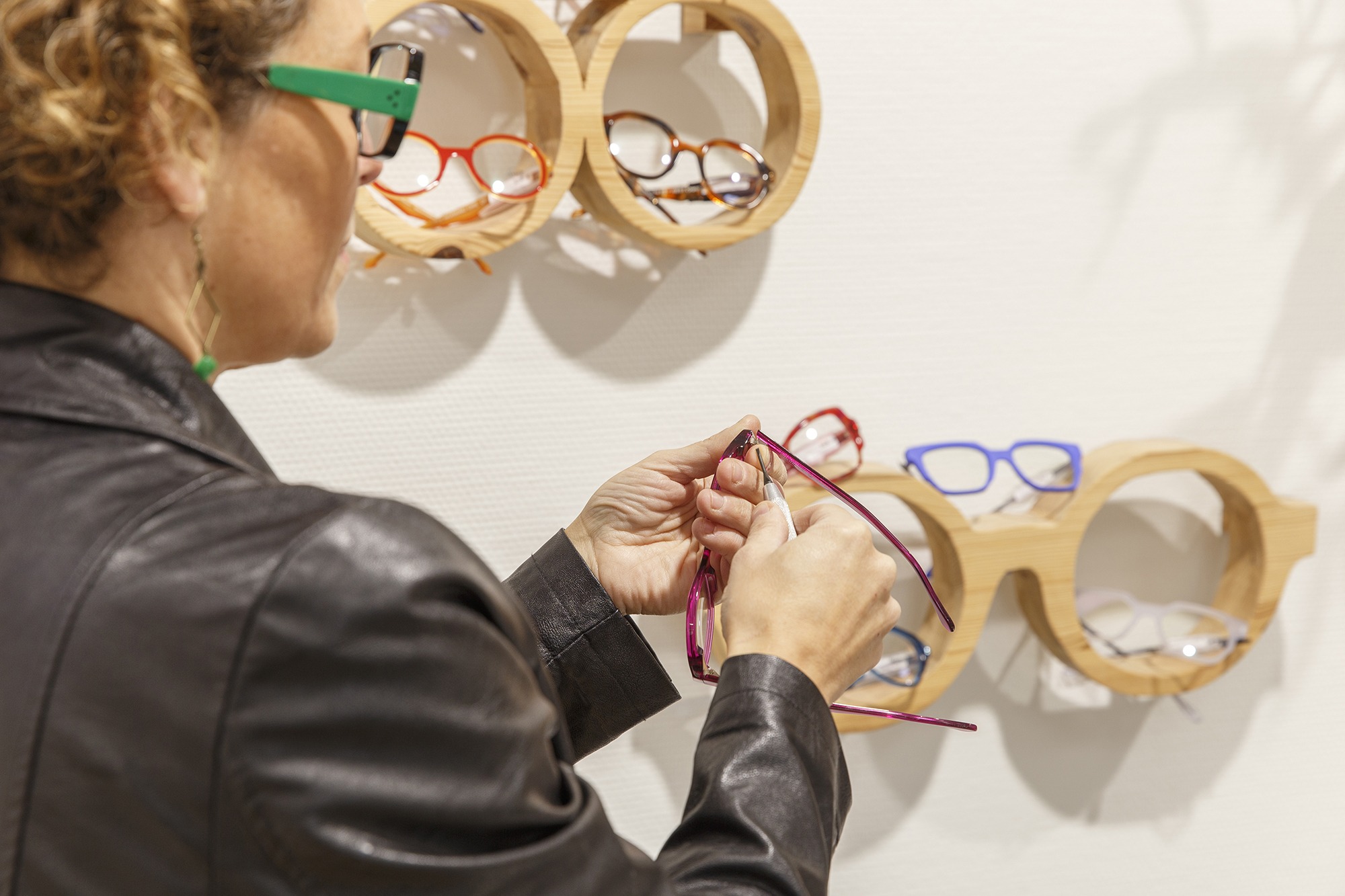 Femme opticienne en train de régler les branches d'une paire de lunettes