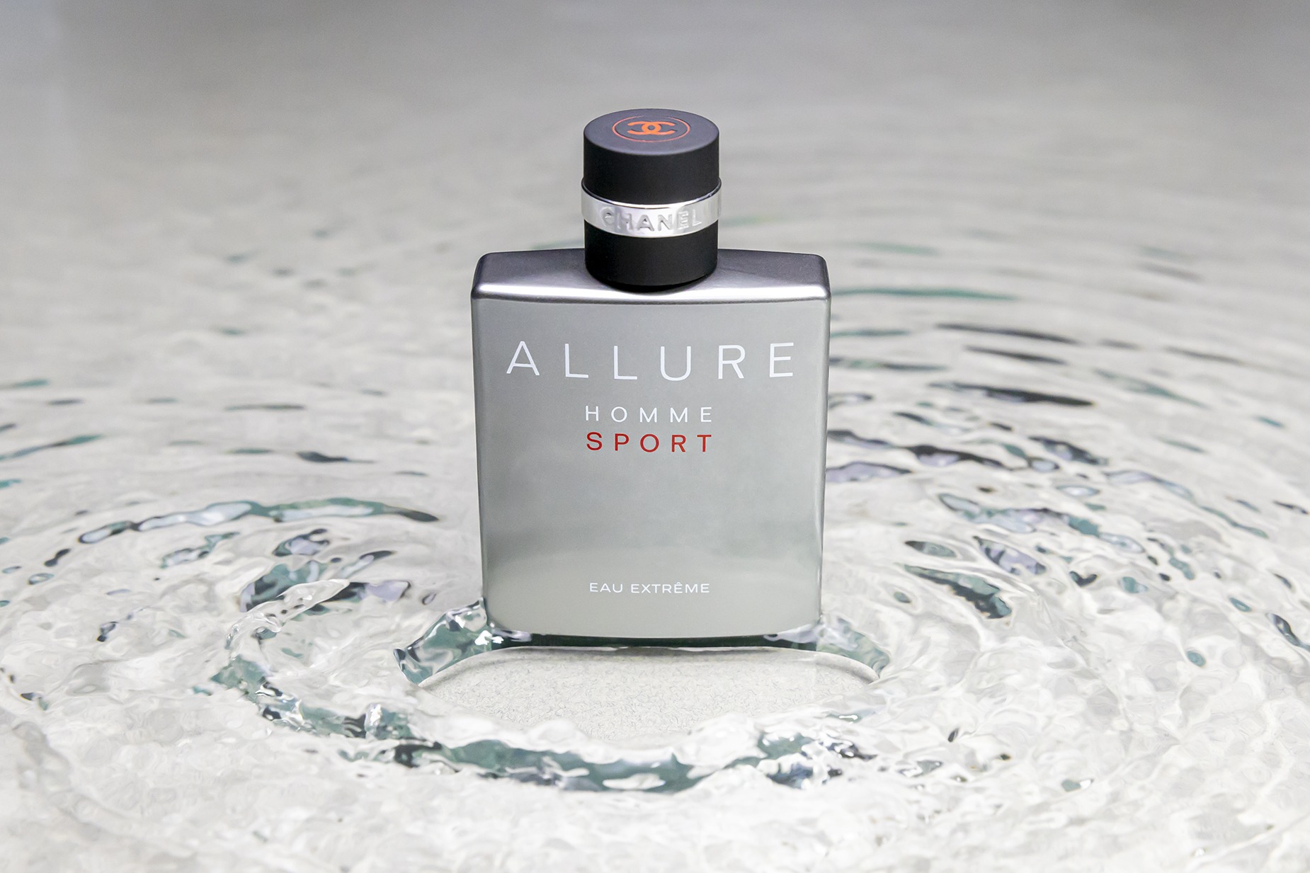 Parfum Channel Allure Homme Sport, photographie prise en studio dans un bac d'eau avec une texture sous l'eau et des petites vagues au pied de la bouteille de parfum.