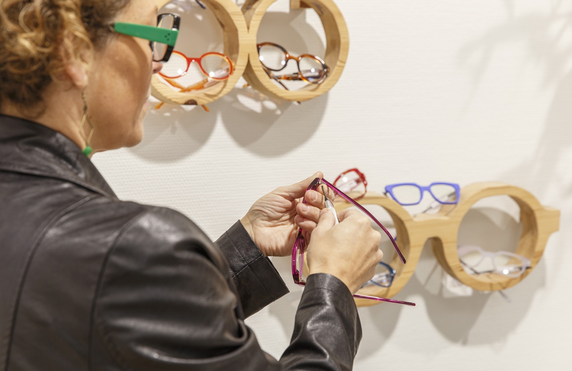 Femme opticienne en train de régler les branches d'une paire de lunettes